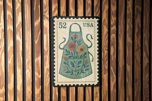 A vintage-style postage stamp featuring a floral apron design is displayed on a wooden wall.