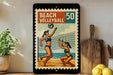 A framed vintage-style poster of two women playing beach volleyball, with a beach volleyball depicted in the center of the frame.