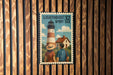 A vintage-style postage stamp featuring a lighthouse and a couple, mounted on a wooden wall.