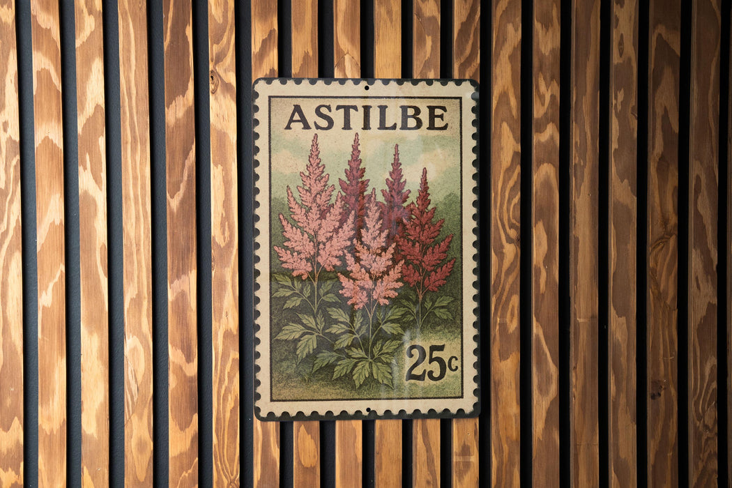 A vintage-style metal stamp with a floral design and the text "ASTILBE" printed on it, mounted on a wooden wall.