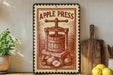 a vintage-style metal sign with the text "APPLE PRESS" and an illustration of an apple press, placed on a wooden shelf next to a potted plant and a wooden cutting board.
