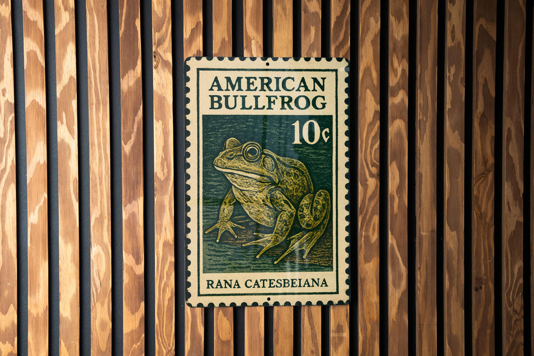 A green and white stamp featuring an American bullfrog, with the text "AMERICAN BULLFROG 10¢" printed on it.