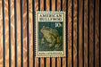 A green and white stamp featuring an American bullfrog, with the text "AMERICAN BULLFROG 10¢" printed on it.