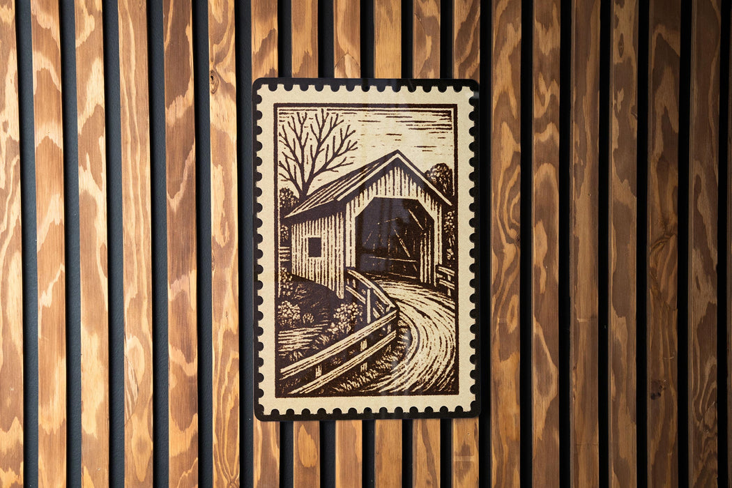 A wooden wall with a framed image of a covered bridge in the center.