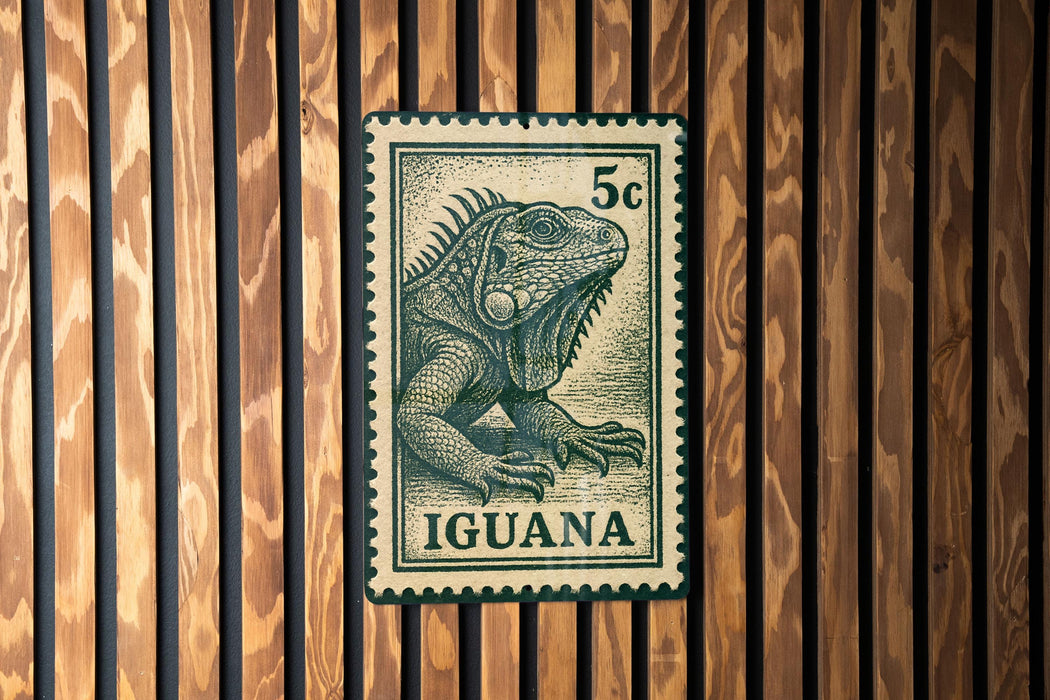 A postage stamp featuring an illustration of an iguana is displayed on a wooden wall.