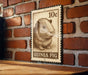 A 10c postage stamp featuring a guinea pig illustration is displayed on a brick wall.