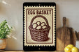 a sign that reads "Egg Basket" with a basket of eggs depicted on it, placed on a shelf next to a wooden cutting board and a potted plant.