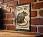 A metal stamp with a picture of a pet rat on it, mounted on a brick wall.