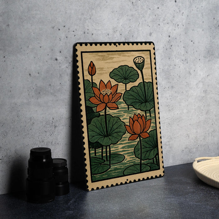 A framed painting of lotus flowers is displayed on a gray wall, with a stack of black camera lenses and a white dish visible to the side.