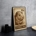 A 10cent postage stamp featuring a guinea pig illustration, placed on a dark surface next to some black camera lenses.