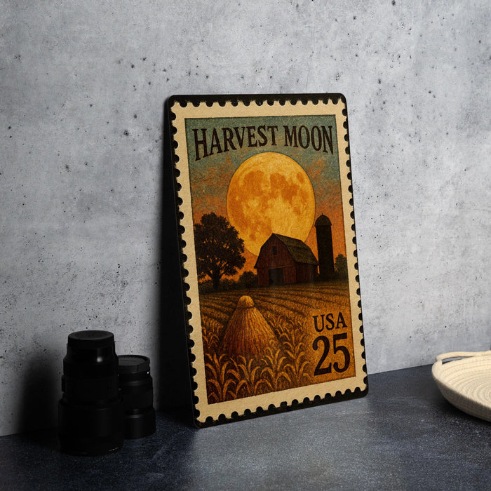 A metal stamp depicting a rural scene with a barn, field, and a full moon, along with the text "Harvest Moon" and "USA 25".