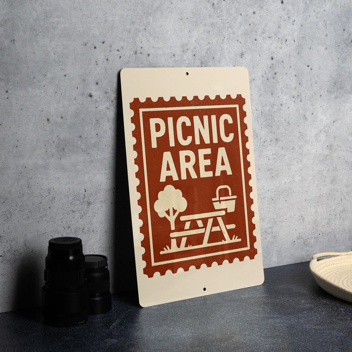A sign that reads "PICNIC AREA" is placed on a table next to some black camera lenses.