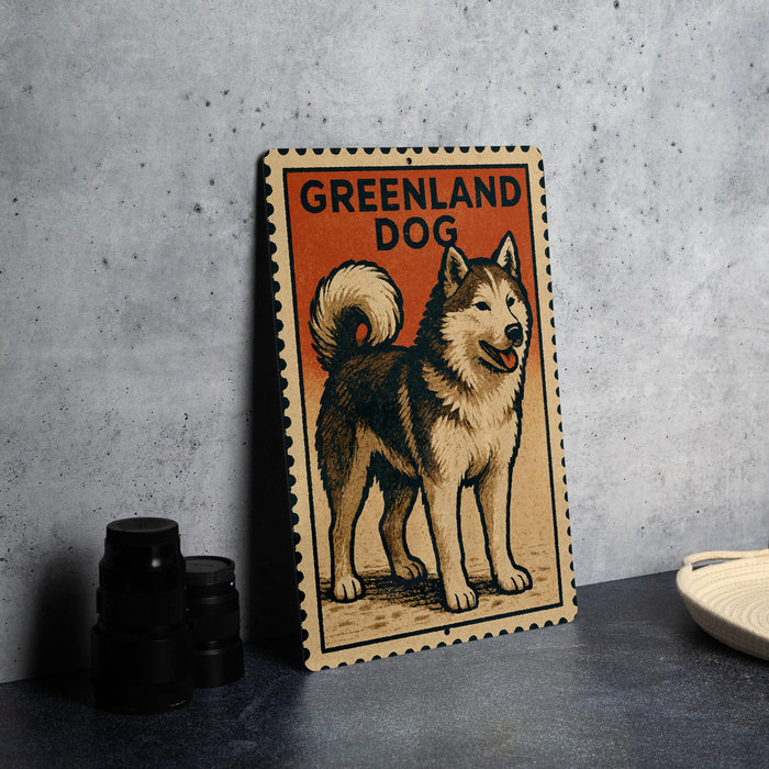 A wooden sign with a picture of a husky dog, labeled "Greenland Dog", is displayed on a table next to some black camera lenses.