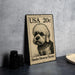 A metal stamp featuring a dandie dinmont terrier dog, with the text "USA 20c" printed on it.