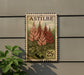 A vintage-style 25c postage stamp featuring a floral design is displayed on a wall, with a plant to the left.