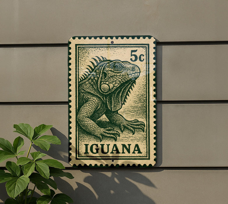 A green and white postage stamp featuring an illustration of an iguana, mounted on a wall next to a plant.