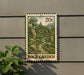 A metal sign with a postage stamp design, depicting a rock garden, is mounted on a wall.