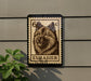 a large stamp-like sign with a dog's head and the word "EURASIER" printed on it, mounted on a wall.