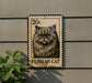 A 20c postage stamp featuring a close-up of a Persian cat is mounted on a wall next to a plant.