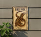 a sign with a lizard illustration, mounted on a wall.