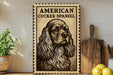 a vintage-style sign depicting an American Cocker Spaniel, with a potted plant to the left and a wooden cutting board to the right.