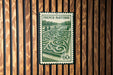 A French postage stamp with a garden design on it, displayed on a wooden wall.