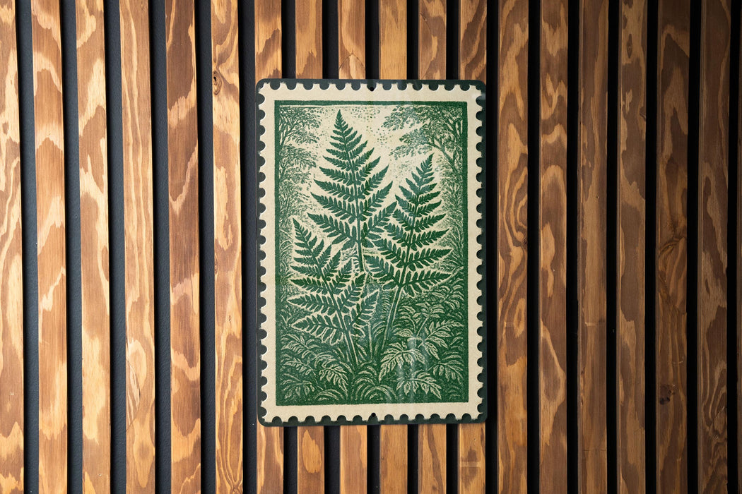 a framed print of a fern plant on a wooden wall.