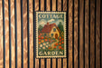 A vintage-style metal sign with a cottage garden illustration is mounted on a wooden wall.