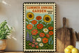 a vibrant poster of a garden with sunflowers and other colorful flowers, displayed on a wall next to a wooden cutting board and a potted plant.