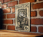 A wooden table with a wooden border, and a framed image of a cat on a brick wall.