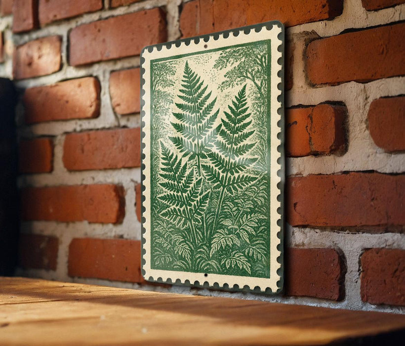 A green and white framed print of a fern plant is displayed on a brick wall, with a wooden table below it.