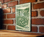 A French postage stamp featuring a garden scene is displayed on a brick wall.