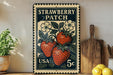 A vintage-style metal stamp featuring a strawberry patch with a potted plant and a wooden cutting board on a shelf.