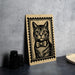 A framed illustration of a cat wearing a bow tie is displayed on a table.