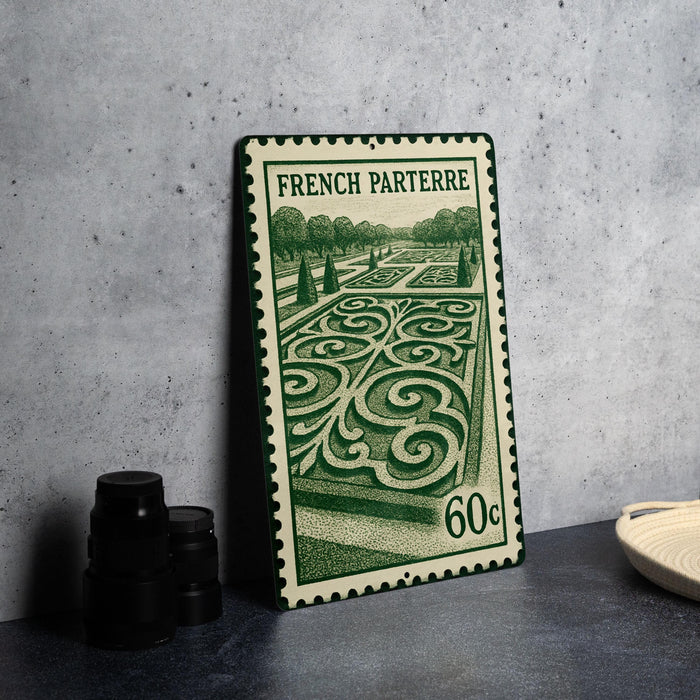 A French postage stamp featuring an ornate garden design, placed on a table next to some black camera lenses.
