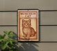 a sign with a cat illustration on it, mounted on a wall.