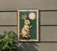 a small, framed illustration of a rabbit holding a white balloon.