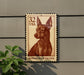 a brown miniature pinscher dog on a brown postage stamp.