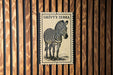 A framed image of a zebra is displayed on a wooden wall.