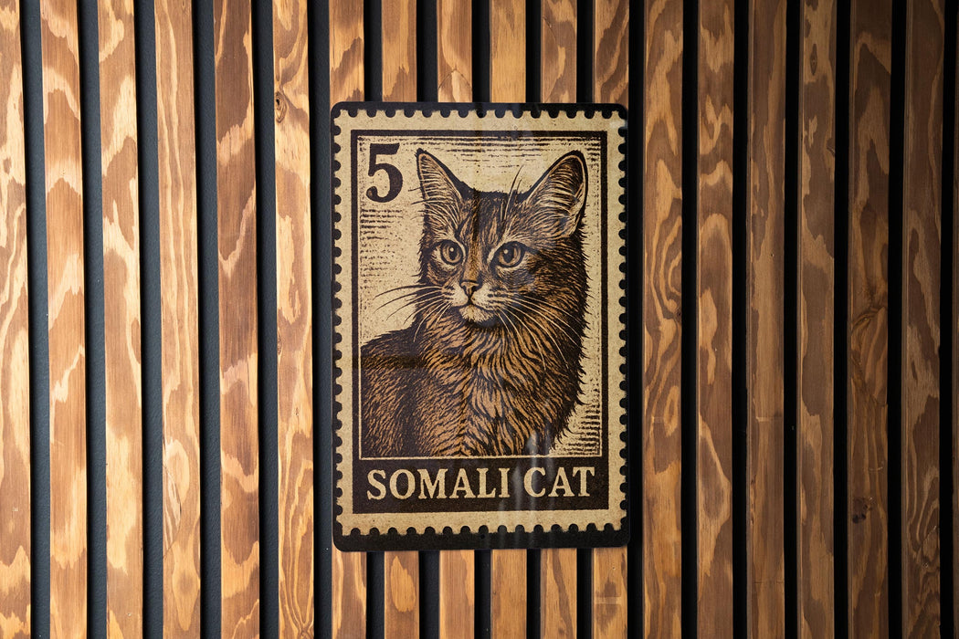 A close-up of a cat's face on a postage stamp, with the word "SOMALI CAT" printed below it.