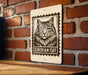 A sign featuring a black and white illustration of a Siberian cat, mounted on a brick wall.