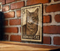 A wooden table with a brick wall in the background, featuring a framed image of a cat on the wall.