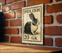 A metal sign with a black and white illustration of a rabbit, mounted on a brick wall.