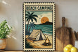 A vintage-style metal sign with a beach camping scene, featuring a tent, palm trees, a campfire, and a sunset over the ocean.