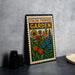 A colorful poster or sign with a garden theme, featuring various flowers and plants, is displayed on a table next to some black camera lenses.