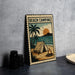 A metal sign with a beach camping scene, featuring a tent, a campfire, palm trees, and a sunset over the ocean.