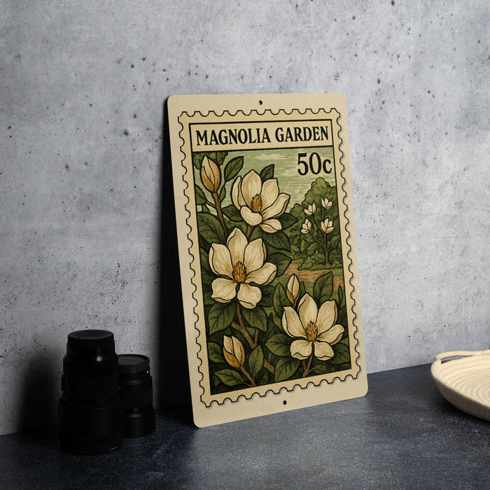 A metal sign with a floral design, featuring magnolia flowers, is displayed on a table.