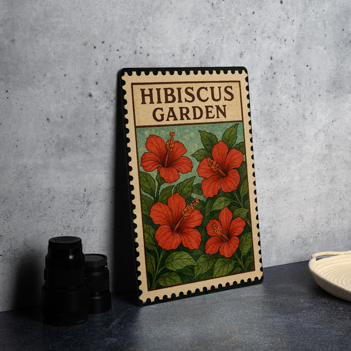 A framed illustration of red hibiscus flowers on a green background, with the text "HIBISCUS GARDEN" on the top and "HIBISCUS" on the bottom.
