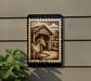 a wooden barn with a horse standing inside, depicted on a black and white postage stamp-like frame.