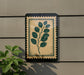 a decorative plant with a leafy green design on a wall, mounted on a gray wall.